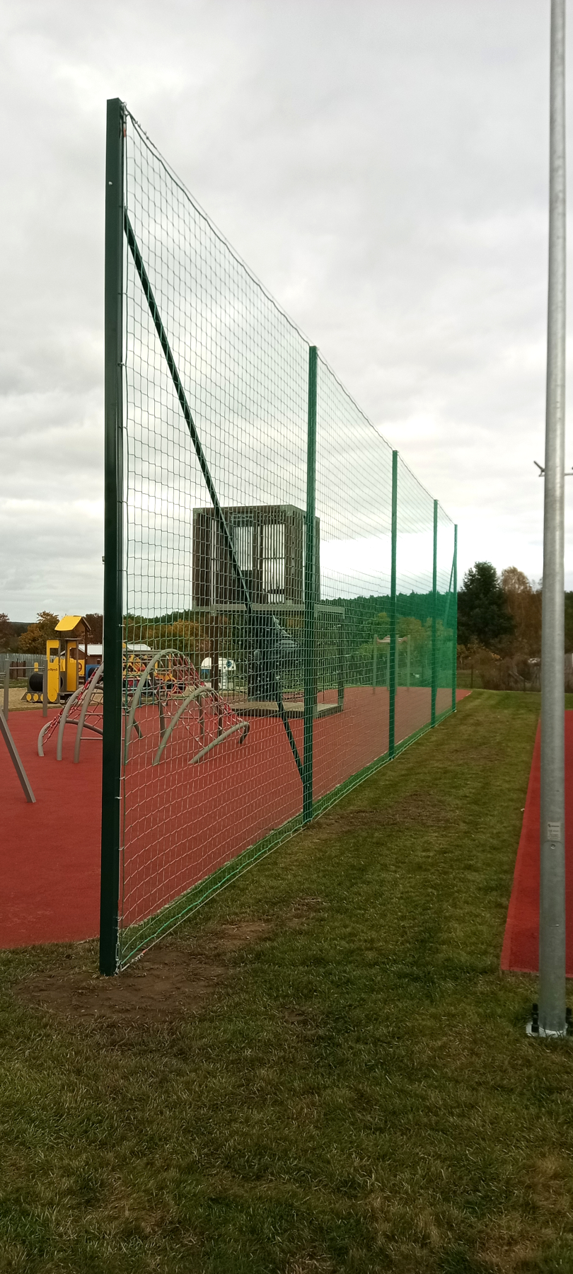 Montaż piłkochwytu o szerokości 20 metrów i wysokości 5 metrów oddzielający boisko sportowe od placu zabaw.
